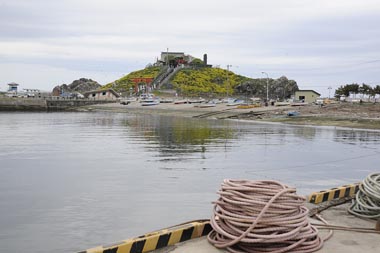 手前の岸壁から蕪島を遠望、傾いたトイレが見えています。
