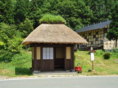 バス停と背景の土壁の小屋がマッチします。願わくば小屋も茅葺きならば最高でした。