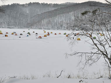 結氷した湖面に並ぶワカサギ釣りのテント。